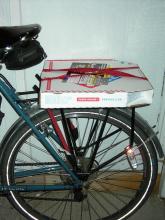 Medium-sized boxed pizza strapped to a rear cargo rack.
